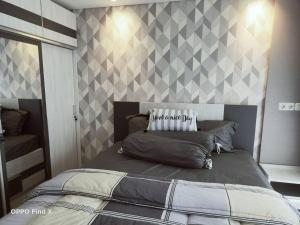 a bedroom with a bed with a diamond patterned wall at Apartemen Skylounge Makassar in Manda