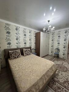a bedroom with a large bed and a chandelier at Уютная квартира комфорт класса111 in Astana