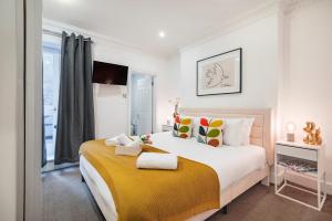 ein Schlafzimmer mit einem großen Bett und einer gelben Decke in der Unterkunft Welcome London Leicester Square in London