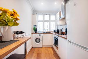 a kitchen with a washer and dryer and a vase of flowers at Welcome London Leicester Square in London