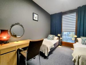 Zimmer mit 2 Betten, einem Schreibtisch und einem Spiegel in der Unterkunft Kolejowa Komfort z parkingiem in Warschau