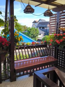 a wooden bench sitting on a balcony with flowers at Ratchiangsaen Flora House in Chiang Mai