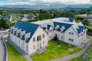 una vista aerea su una grande casa bianca con tetti blu di The Steadings, Aviemore Luxury 5 star rated 3 Bed with home cinema garden and parking ad Aviemore