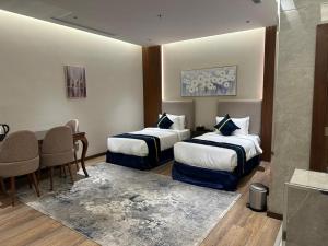 Cette chambre comprend 2 lits et une table. dans l'établissement فندق سنبات بلاتينيوم, à Jazan