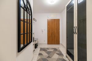 a hallway with a wooden door and a mirror at Horyzont Apartamenty-ANTON-Piękny apartament blisko centrum, dwie sypialnie, prywatny garaż in Kołobrzeg