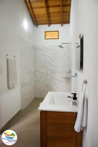 een witte badkamer met een wastafel en een douche bij El Encanto de las Aguas in Necoclí