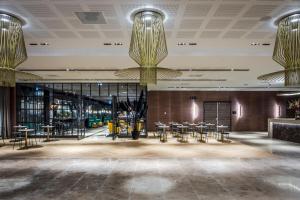 een lobby met tafels en stoelen en kroonluchters bij Van der Valk Hotel Enschede in Enschede