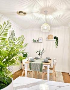 a white dining room with a table and chairs at Cosy 3BR House, 7 mins drive to Macquarie Centre, 5 stars on AirB&B in Sydney