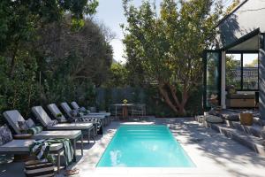 a backyard with a pool with chairs and a table at Twice Central Guest House in Stellenbosch