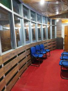 a row of blue chairs in a room with windows at Balaji Guest House in Shillong