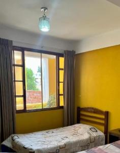 - une chambre avec des murs jaunes, une fenêtre et un lit dans l'établissement Urbano, à Tarija