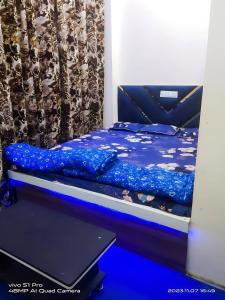 a bed with a blue comforter and a laptop on a table at PRABHU PALACE in Ujjain
