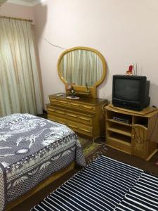 a bedroom with a bed and a tv on a dresser at Dr milad shokralla multiple central flats in Luxor