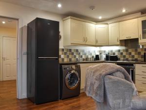 a kitchen with a refrigerator and a washing machine at Walnuts Nest in Minehead