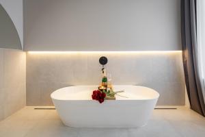 a white bath tub with a bottle of champagne and flowers at You Boutique Suites, Best Location by BQA in Budapest