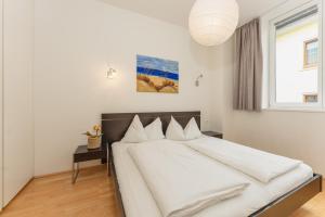 a bedroom with a bed with white sheets and a window at Appartements Tamino by Schladming-Appartements in Schladming
