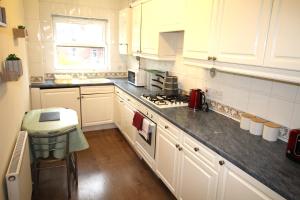 a kitchen with white cabinets and a stove top oven at Doncaster - Town Centre - 2 Bedrooms & Sofa Bed - Very Quiet Location in Doncaster