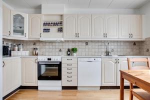 a white kitchen with white cabinets and a table at Vikingavägen 75 in Gävle