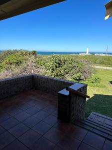 a patio with a bench and a view of the beach at Lighthouse Villa in Cape St Francis