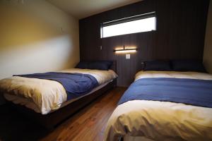 two beds in a bedroom with a window at SAKURA YAKUSHIMA in Yakushima