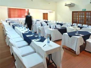 a room full of tables and chairs with a man in the background at Limpopo Guest Manor in Polokwane