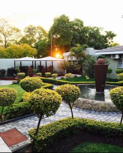 a garden with a pond with trees and bushes at Limpopo Guest Manor in Polokwane