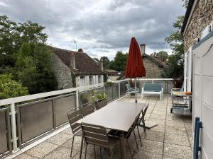 a patio with a table and chairs and an umbrella at Appartement Terrasse Barbizon in Barbizon