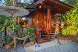 a wooden cabin with a staircase and an umbrella at Suk Sabai Homestay in Sukhothai