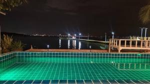 uma piscina à noite com um corpo de água em เรือนตะวัน เกาะล้าน RueanTawan Kohlarn em Ko Larn