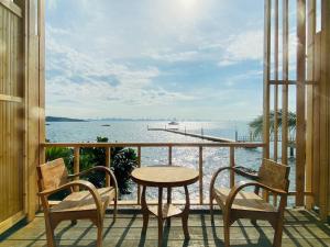 een balkon met een tafel en stoelen en uitzicht op het water bij เรือนตะวัน เกาะล้าน RueanTawan Kohlarn in Ko Larn