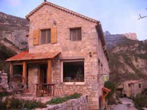 una vecchia casa in pietra con montagne sullo sfondo di Un cadre magnifique, au cœur du Verdon a Castellane