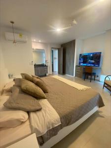 1 dormitorio con 1 cama grande con almohadas y TV en casa de descanso pto velero, en Barranquilla