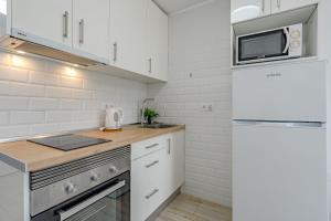cocina blanca con nevera y microondas en Apartamentos en El Dorado, en Playa de las Américas