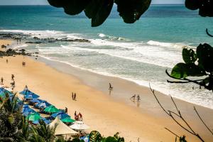 una spiaggia con ombrelloni e persone sulla spiaggia di SAMO Hostel a Pipa