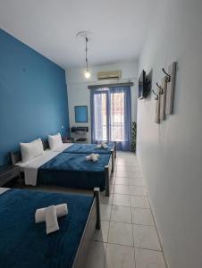 um quarto com 2 camas e uma parede azul em Hotel Theoxenia em Árgos