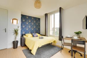 a bedroom with a bed with a blue headboard and a desk at Studio Au Bord du Canal (4B) *Paris*Disney* in Chelles