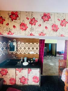 a kitchen with a sink and red flowers on the wall at Sahara premium family homestay in Mysore