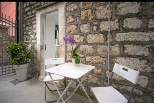 a white table and two chairs in front of a brick wall at Apartments Lotti 2 in Stari Grad