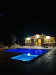 Camping auberge palmeraie d'amezrou في زاكورة: حمام سباحة في الليل مع مبنى في الخلفية