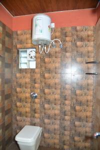 a bathroom with a toilet and a brick wall at Panchavati Home Stay in Sringeri
