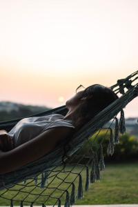 une femme qui se couche dans un hamac avec le coucher du soleil en arrière-plan dans l'établissement Quinta Raposeiros, à Santo Isidoro