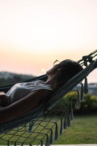 una mujer tendida en una hamaca con la puesta de sol en el fondo en Quinta Raposeiros, en Santo Isidoro