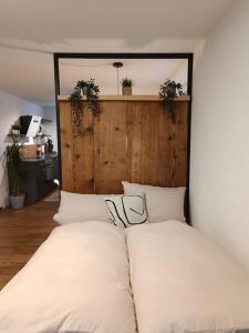 Bett mit weißen Kissen in einem Zimmer in der Unterkunft Altholzapartment in Kempten in Waltenhofen