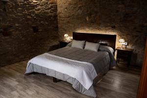um quarto com uma cama grande numa parede de pedra em Masia Casa Nova de n'Illa em Montseny