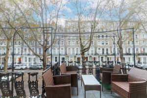 a patio with chairs and tables in front of a building at Harrods Flats in London