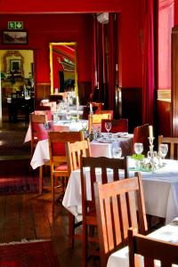 a restaurant with white tables and chairs and red walls at Die Tuishuise & Victoria Manor in Cradock