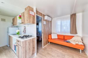 una piccola cucina con divano arancione e piano cottura di San Benedetto Camping Relais a Peschiera del Garda