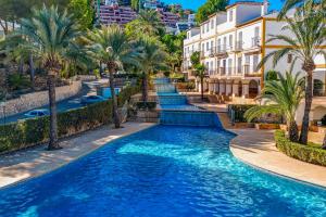 una piscina en un complejo con palmeras y edificios en Ruhiges Eckreihenhaus mit Pool, en Pedreguer