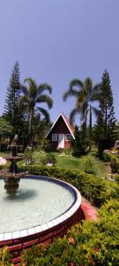 a fountain in a garden with a house in the background at RESORT CHALÉ DA PRATA in Curvelo