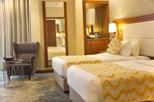 um quarto de hotel com duas camas e uma cadeira em Taj Al Worood Hotel em Jeddah